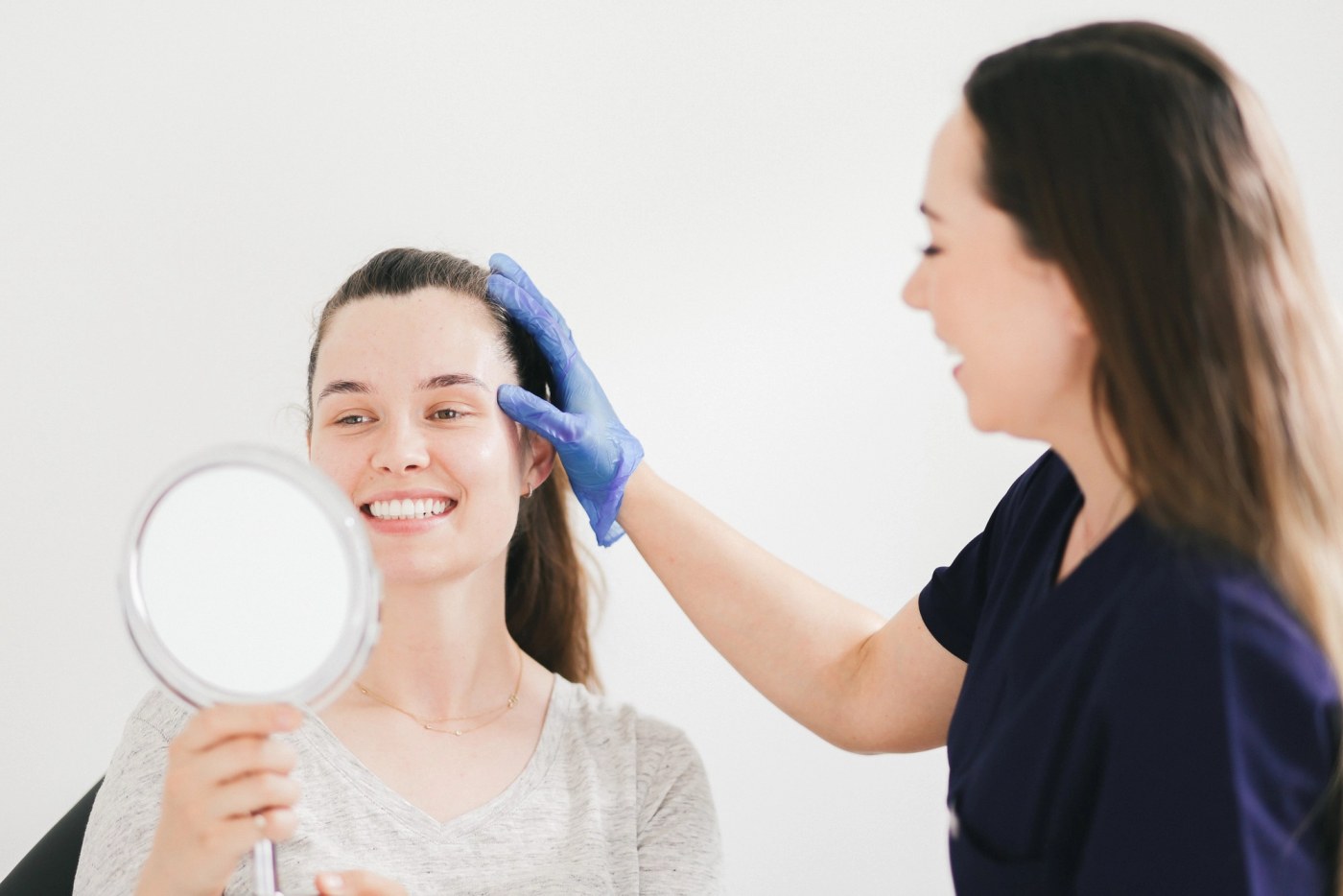 Jenny with a patient holding a mirror during an appointment